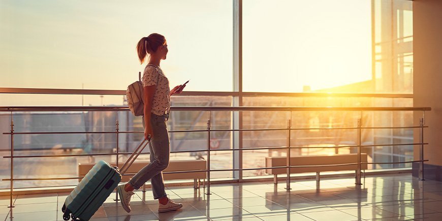 Vrouw loopt door de luchthaven met paspoort en instapkaart in de hand