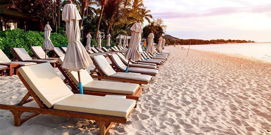 Ligstoelen in gouden licht op Chaweng Beach op Koh Samui, Thailand.