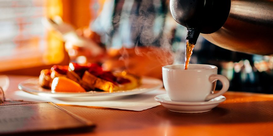 Man in restaurant eet wafels en drinkt koffie