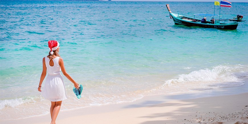 Vrouw loopt op het strand in Thailand met kerstmuts op