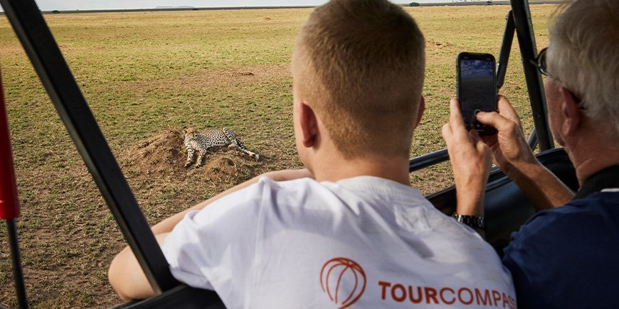 Twee mannen kijken naar cheeta's op de savanne in de Serengeti