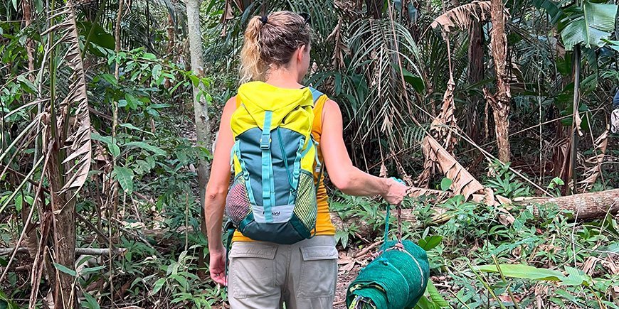 Jude wandelend met haar slaapzak in het Amazonewoud