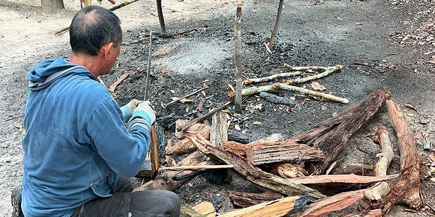 man maakt vuur in de jungle