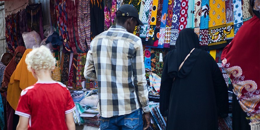 Jongen loopt tussen de lokale bevolking op de markt in Stone Town