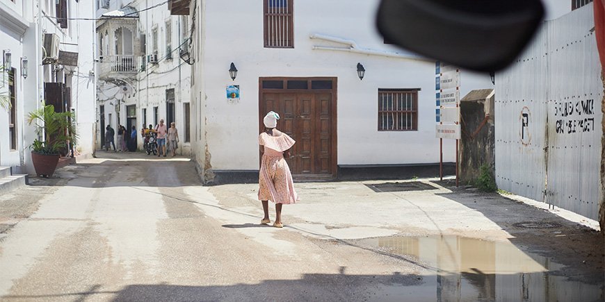 Vrouw in jurk loopt door de straten van Stone Town