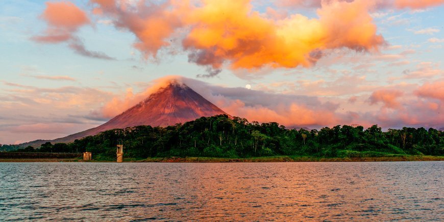 De zon gaat onder boven de vulkaan Arenal en het meer